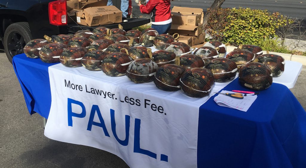 Community 6 A table laden with turkeys, promoting "More Lawyer. Less Fee. PAUL." for a Las Vegas personal injury law firm giveaway event.
