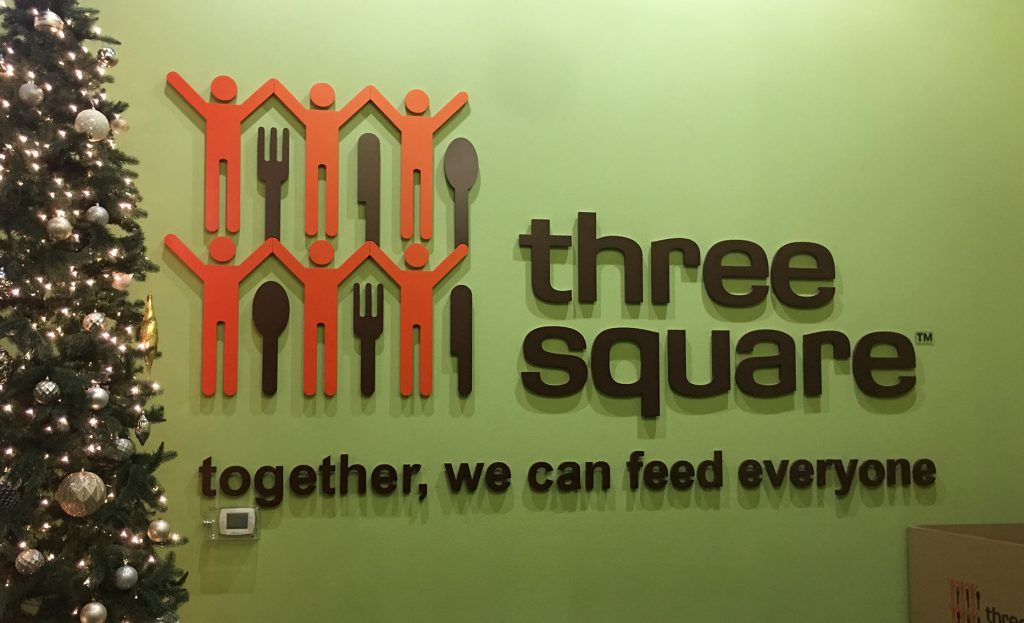 A photo of the "Three Square" logo, a Las Vegas food bank, symbolizing the law firm's dedication to serving the community and seeking justice for personal injury victims, with a Christmas tree suggesting a focus on support during the holiday season.