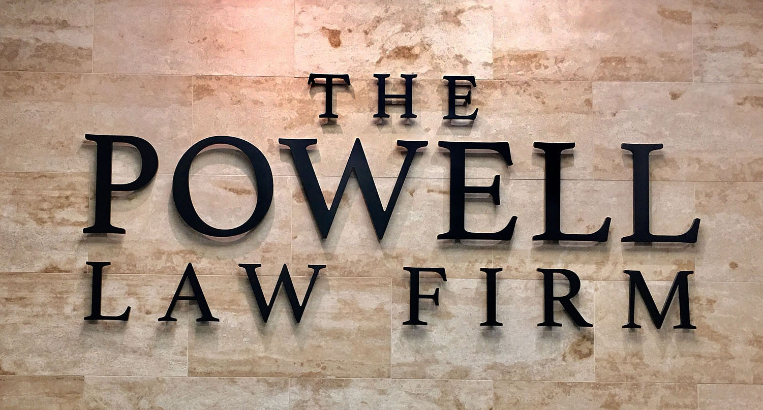 Close up of "The Powell Law Firm" signage in black lettering on a tan tiled wall, representing a personal injury law firm in Las Vegas.