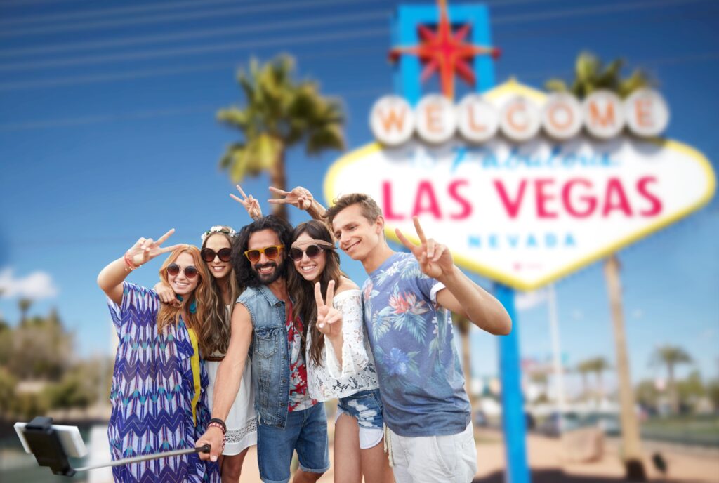 A group of five young adults are posing for a selfie with the Welcome to Las Vegas sign in the background, suggesting a potential personal injury case related to tourism or accidents in Las Vegas.