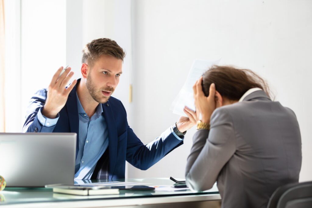 A frustrated man in a blue suit gestures with papers towards a woman in distress with her hands on her head, depicting a potential client overwhelmed by the complexities of a personal injury case.