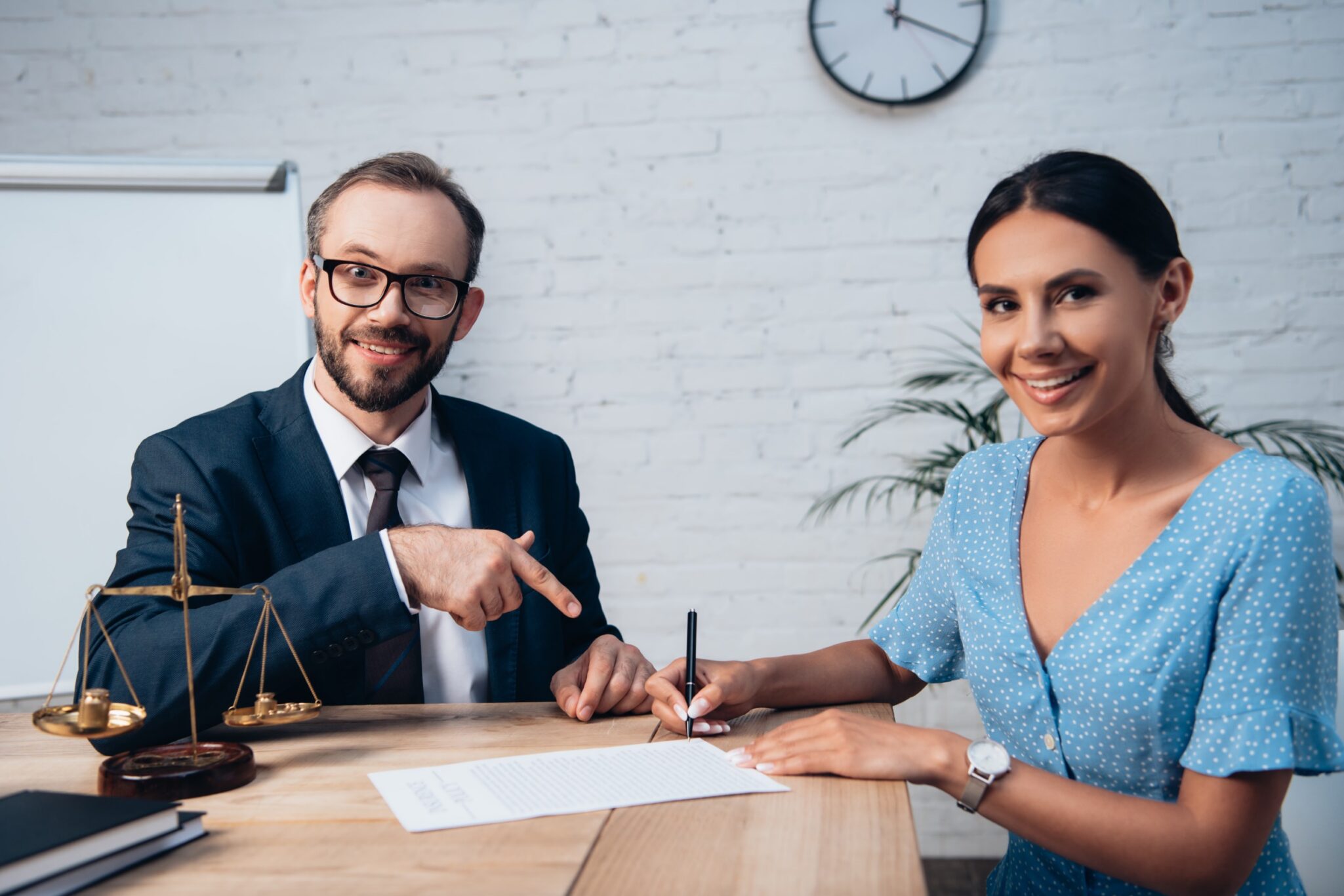 Smiling man pointing at a document while a woman signs, representing legal assistance for personal injury claims in Las Vegas.