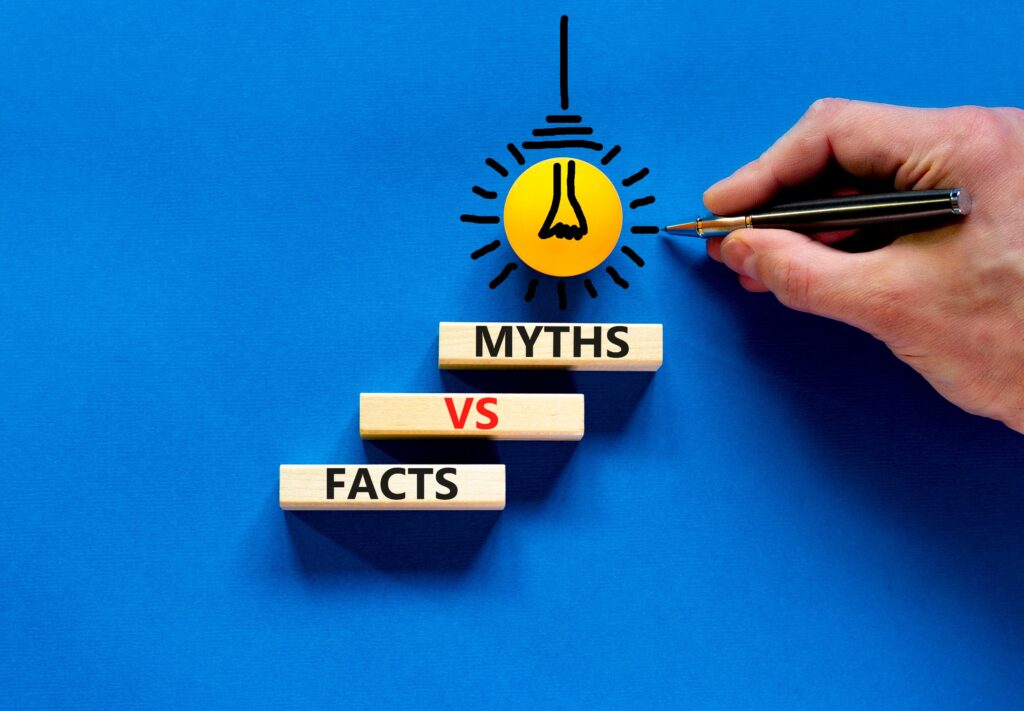 Hand with pen pointing at "Myths" written on wooden blocks stacked on top of "Facts" on blue background, representing debunking common misconceptions in personal injury law.