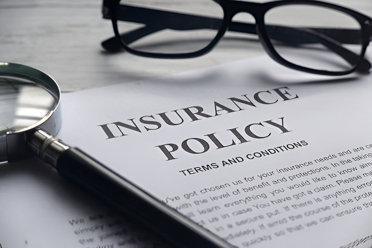 Close-up of an insurance policy document with a magnifying glass and glasses, representing the detailed investigation and legal expertise provided by a Las Vegas law firm specializing in personal injury claims.